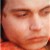 Pixelated close-up of a human face showing eyes, nose, and mouth with warm skin tones and blurred background.