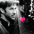 Pixelated grayscale image of a person with short hair holding a bright pink heart symbol against dark background.