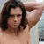 A shirtless man with long dark hair holds his hands behind his head in a static pose, with text overlays appearing in the top-right quadrant.