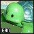 Pixelated green creature with single dark eye, leafy appendages, and white text 'FAN' in bottom-left corner against blurred background.