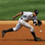 Baseball player in white uniform running on dirt field with green grass background, captured across three showing motion progression
