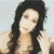 A pixelated image of a person with long dark hair, light skin, and a neutral expression, wearing a light-colored top against a pale background.