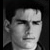 Pixelated grayscale portrait of a person with short hair, neutral expression, and dark background, cropped to show head and shoulders.