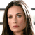 A pixelated close-up of a person with long dark hair, light skin, and a neutral expression against a blurred background.