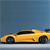 Yellow sports car in side profile view against blue background, positioned on light gray surface with visible wheels and black roof.