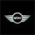 Pixelated silver winged emblem with circular center on black background, featuring two symmetrical wing-like extensions and a central dark oval shape.