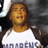 Pixelated static image of a person wearing a white shirt with dark sleeves and partially visible text, set against a dark background.