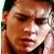 Pixelated close-up of a person's face with brown hair and dark eyes, wearing a dark collar, against a light background.