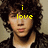 A pixelated image of a person with curly hair wearing a dark jacket over a light shirt, with yellow text overlays reading 'i love nick jonas (33)' across different sections of the face.