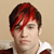 Static pixelated image of a person with red and black hair wearing a white shirt against a beige background.