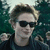 Pixelated image of a person with dark hair and sunglasses against a green background.