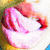 Pixelated pink and red cartoon character with closed eyes and a wide smile, set against a blurred background of yellow and brown tones.