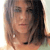 A pixelated close-up of a person with shoulder-length brown hair, light skin, and a neutral expression against a light background.