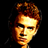Pixelated static icon of a person's face with warm-toned hair and skin against black background, rendered in low-resolution 256x256 pixels.