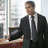 A pixelated image of a man in a suit standing near a desk with text overlays on black and gray backgrounds.