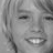 Pixelated grayscale close-up of a person's face showing eyes, nose, mouth with visible teeth, and hair strands on the left side.