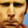 Pixelated close-up of a human face with brown eyes, nose, and mouth against warm-toned background.
