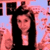 Pixelated image of a person with long dark hair wearing a black top against a pink and blue background.