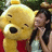 A pixelated image shows a large yellow bear with black nose and eyes, wearing red clothing, next to a person in light-colored top with dark hair.