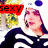 A pixelated image of a person in a black and white striped top with a white hood, standing outdoors near greenery.