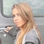 A woman with long blonde hair in a gray top, shown in three with slight head movement against a blurred background