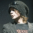 Pixelated image of a person with brown hair wearing a dark gray hooded garment against a dark background.