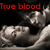 Pixelated image with red text 'True blood' above a grayscale figure holding a skull-like object against a black background.