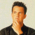 Pixelated portrait of a person with short dark hair wearing a dark jacket over a light shirt against a light background.