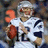 Pixelated image of a football player in white uniform holding a brown ball, with red text 'HERO TOM' on blue background.