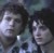 Two pixelated figures with dark hair and light skin tones appear in a low-resolution static image with a dark background.