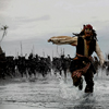 A pixelated figure in pirate attire wades through shallow water, holding a wooden plank horizontally with both hands, while a large dark formation of figures stands in the background under a pale sky.