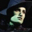 Pixelated image of a stylized face with light skin tone, dark hair, and a wide open mouth showing teeth, set against a dark background with blue and green accents.