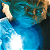Pixelated static image of a figure in blue attire with light-colored hair against dark background, showing partial upper body and arm movement.