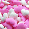 A dense cluster of small heart-shaped objects in pink and white hues, tightly packed together with no visible background or surrounding elements.