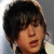 Pixelated close-up of a person with dark tousled hair, light skin tone, and closed eyes against a gradient background.