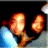 Pixelated image of two orange-brown figures with glowing faces against a dark background, one figure emitting blue light from its lower body.