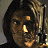 Pixelated close-up of a person with dark hair holding a glowing object near their face against a muted background.