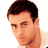 Pixelated static image of a person's head and shoulders with short dark hair, light skin tone, visible facial features including eyes, nose, mouth, and ear, against a plain white background.