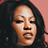 A pixelated promotional image featuring a person with long dark hair against a solid background, accompanied by text announcing an album release date.