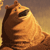 Pixelated orange-brown dog with open mouth and raised paw against gradient background, rendered in low-resolution style