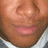 Close-up of a person's face showing closed eyes, pink lips, and light brown skin tone with visible pores.