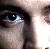 A pixelated close-up of a person's eye with dark eyeliner, showing partial facial features and a bright reflection in the eye.
