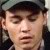 Pixelated close-up of a person wearing a dark cap and dark clothing, with visible facial features and a neutral expression.
