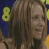 Animated sequence of a person with long brown hair holding a microphone against a dark blue background with repeating yellow text.