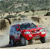 Pixelated static image of two vehicles on a road with a blurred background, one blue and one red, positioned side-by-side.