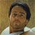 A pixelated close-up of a person with dark hair and a light-colored shirt against a brown background.