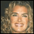 Static pixelated image of a person with curly light brown hair and closed eyes, rendered in low-resolution 256x256 pixels with visible dithering and anti-aliasing on facial features.