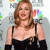A pixelated image of a person with long brown hair wearing a black strapless top and black sleeves, standing against a blurred background with colorful shapes.