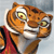 Pixelated tiger head with orange-brown stripes, white facial markings, and yellow eyes, wearing a red garment against a light gray background.