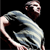 Pixelated figure in dynamic pose with bent arm and torso, dark background, light-colored clothing, visible facial features including eyes and mouth.